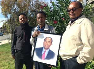 In this Dec. 5, 2015, file photo, family members of Isaac Amanios, from left, Robel Tekleab, Fessehatsion Gebreselassie and Abraham Amanios hold a portait of Isaac Amanios in Fontana, Calif. Isaac Amanios was killed during a Dec. 2, 2015 attack at his work holiday party at a social services center in San Bernardino, Calif. When Obama lands in Southern California Friday, Dec. 18, before heading to Hawaii for his annual Christmas vacation, he will encounter a group of families still burying their dead. Some are just beginning to grapple with what happened while others describe being in a state of continued shock. (AP Photo/Christine Armario, File)