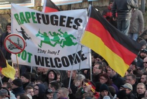 Right-wing demonstrators hold a sign "Rapefugees not welcome - !Stay away!" and a sign with a crossed out mosque as they march in Cologne, Germany Saturday Jan. 9, 2016. Womens rights activists, far-right demonstrators and left-wing counter-protesters all took to the streets of Cologne on Saturday in the aftermath of a string of New Years Eve sexual assaults and robberies in Cologne blamed largely on foreigners. (AP Photo/Juergen Schwarz)